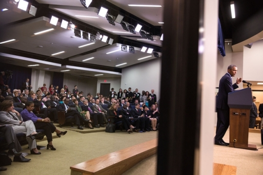 Audience members are reflected in a glass pane as President Barack Obama delivers remarks at the Global Health Security Agenda Summit in the Eisenhower Executive Office Building South Court Auditorium, Sept. 26, 2014. (Official White House Photo by Pete Souza)
