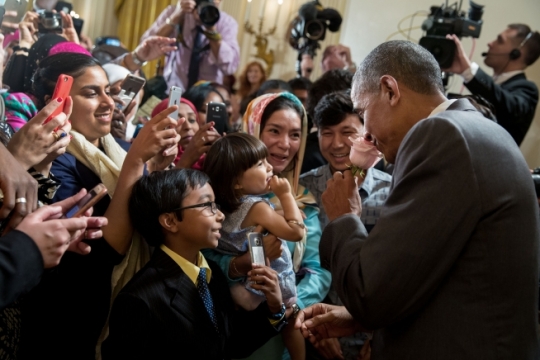 President Barack Obama smells a rose given to him by Sophia Ahmadi, 2, as her parents, Zainab Ahmadi and Mohammad Ahmadi, look on during the Eid al-Fitr reception in the East Room of the White House, July 21, 2016. (Official White House Photo by Pete Souza)